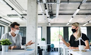 Employees wearing masks in the office and social distancing