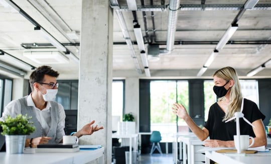 Employees wearing masks in the office and social distancing