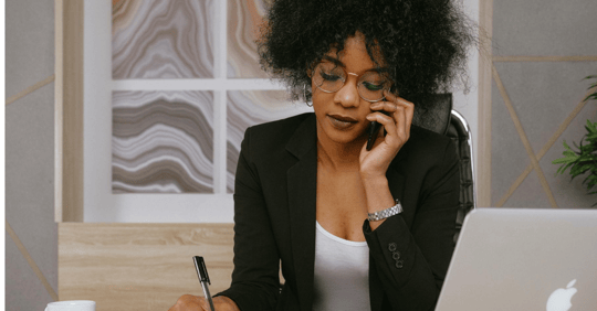 Woman writing while on the phone